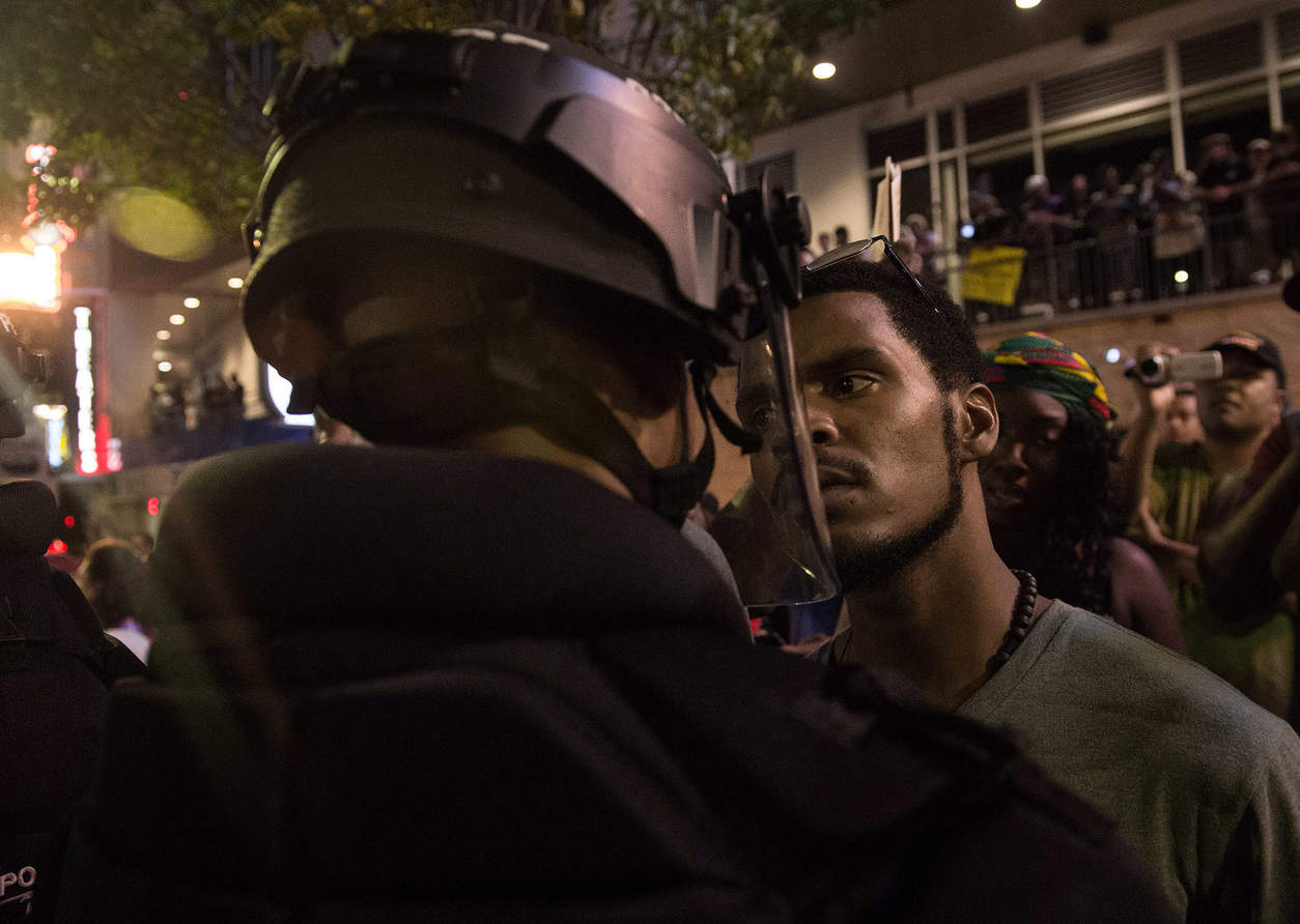 A protester stares at riot police during a demonstration against police brutality in Charlotte, North Carolina, on September 21, 2016, following the shooting of Keith Lamont Scott the previous day. A protester in Charlotte, North Carolina was fatally shot by a civilian during a second night of unrest after the police killed a black man, officials said. / AFP PHOTO / NICHOLAS KAMMNICHOLAS KAMM/AFP/Getty Images           NYTCREDIT: Nicholas Kamm/Agence France-Presse -- Getty Images